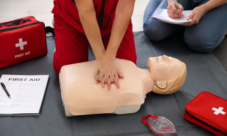 Formação em primeiros socorros com prática de reanimação cardiopulmonar (RCP) em manequim e material de emergência médica.